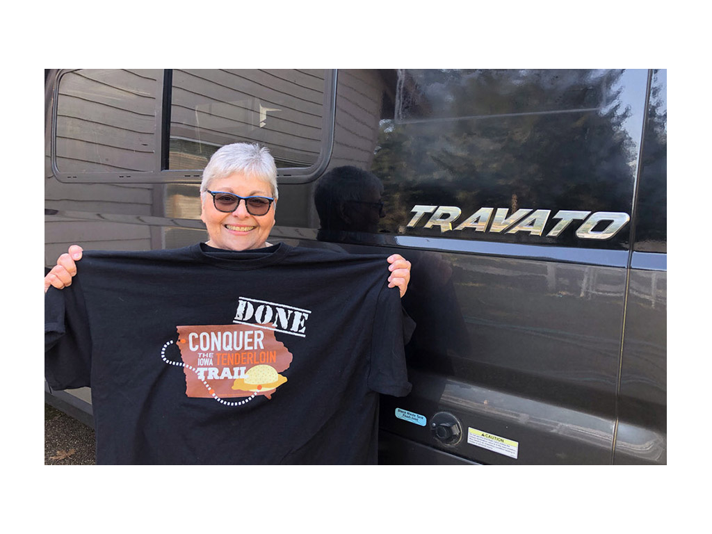 Sue Ann holding up Pork Tenderloin Trail T-shirt in front of Travato