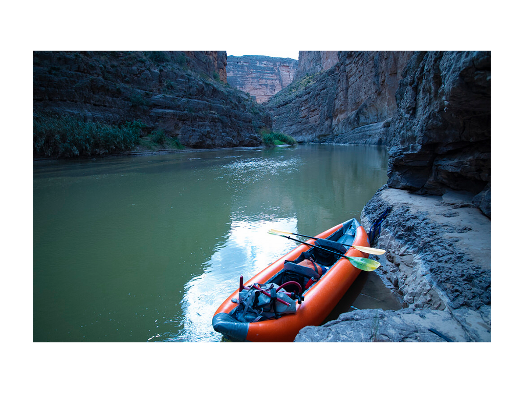 Orange kayak in Rio Grande River surrounded by mountains