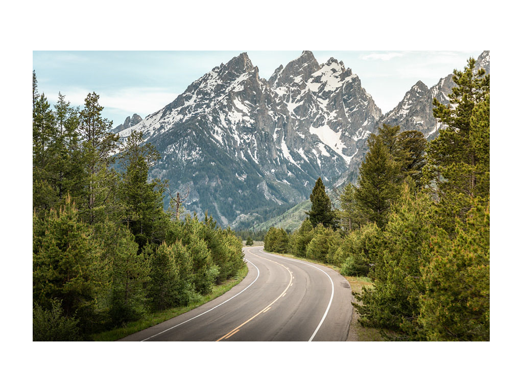 Mountains ahead and tress to the right and left on Tetons Scenic Road