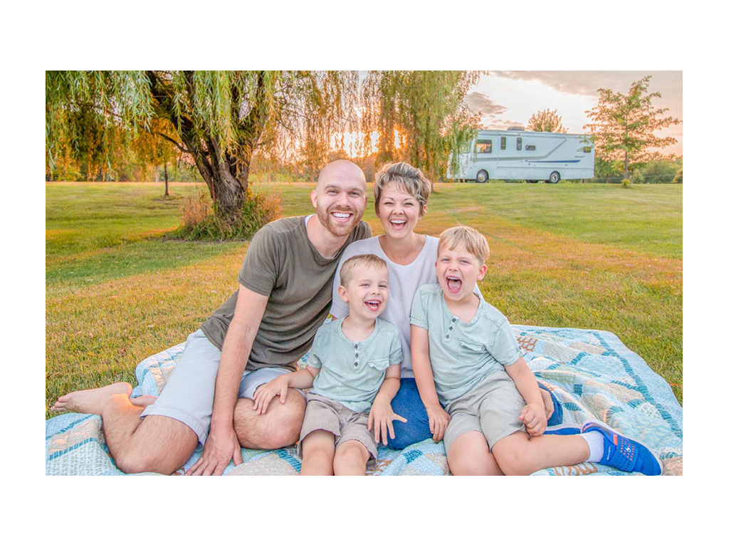 Farish family sitting smiling with beautiful trees and Winnebago Intent in the background