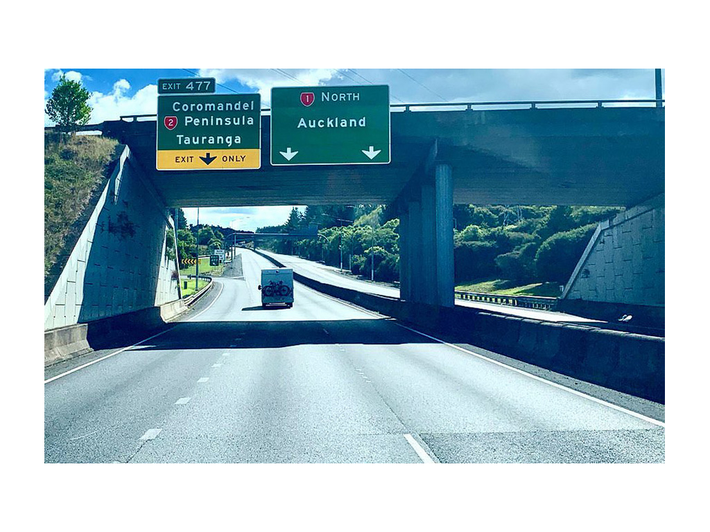 One car driving down empty road in New Zealand