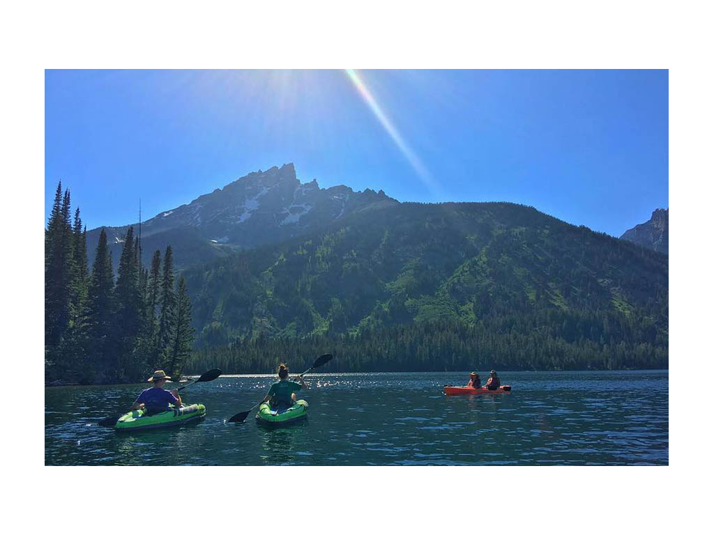 Alyssa and Heath and two friends in double kayak kayaking with mountain view