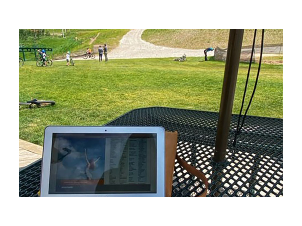 Laptop sitting on picnic table at a park