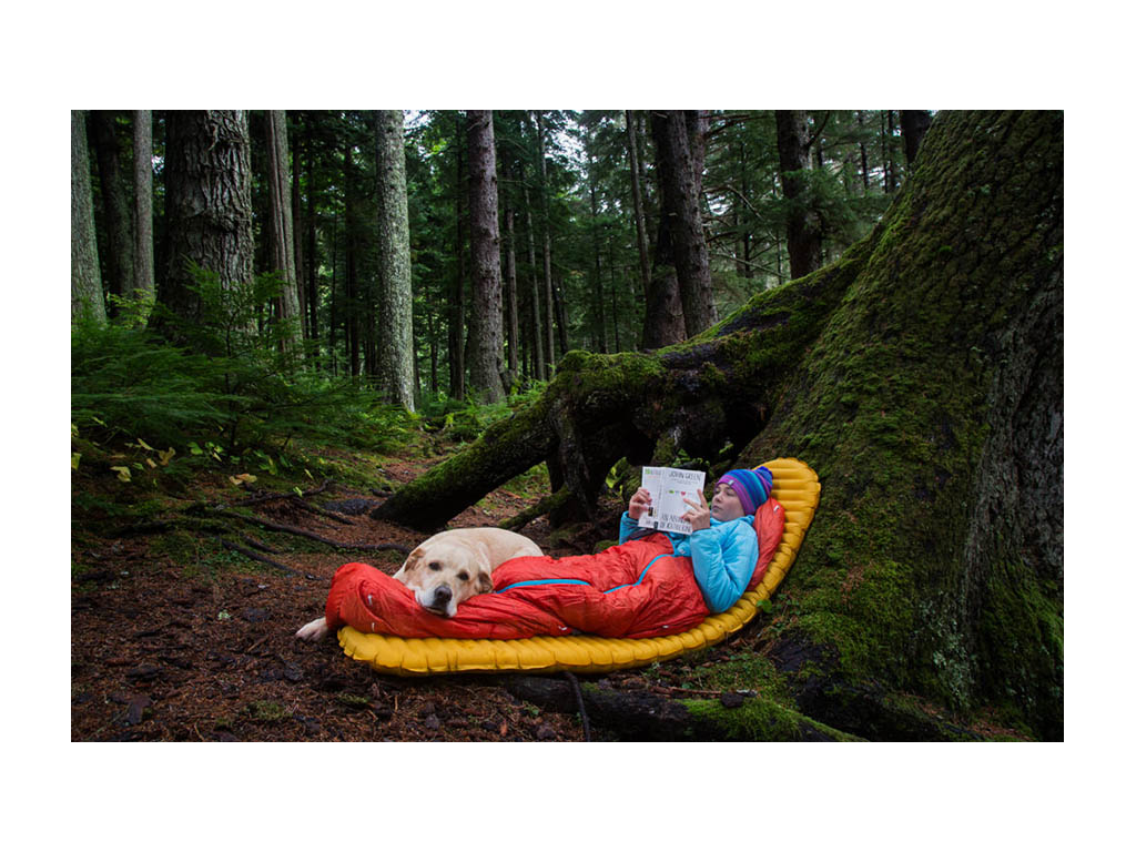 Abby and Tucker laying next to tree reading a book