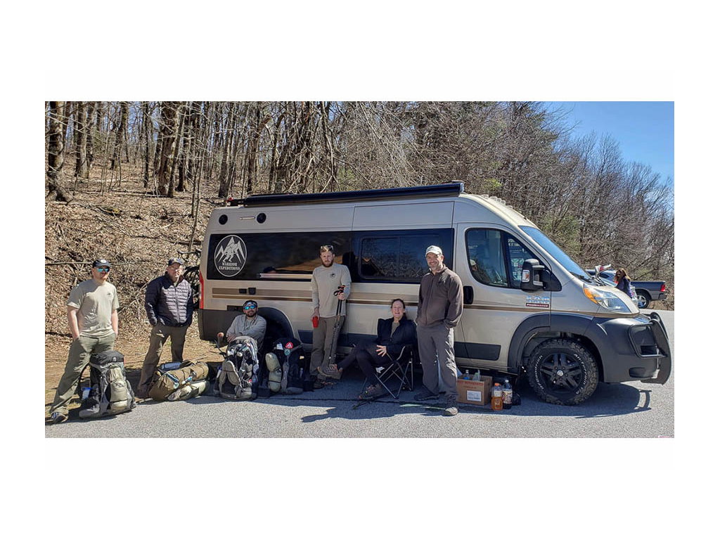 Warrior Expeditions group sitting in front of Winnebago Travato with gear