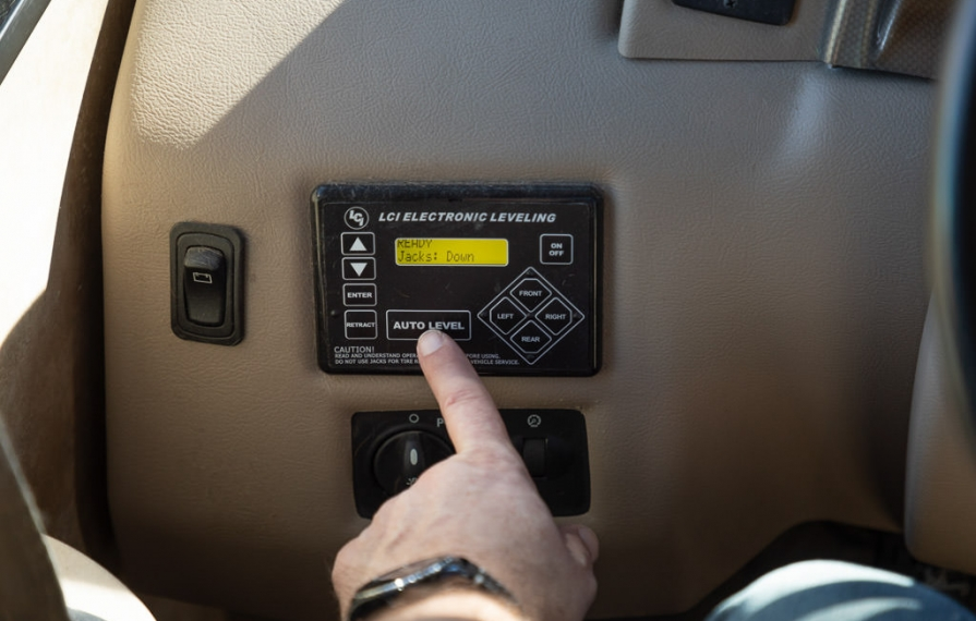 Pressing the auto level button on the auto-leveling system to level RV