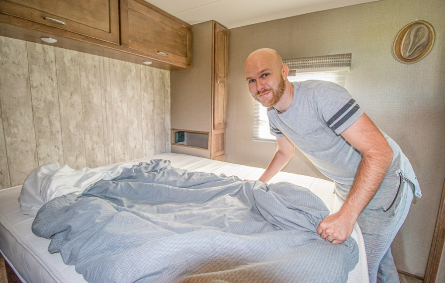 Young man makes the bed of Winnebago Intent