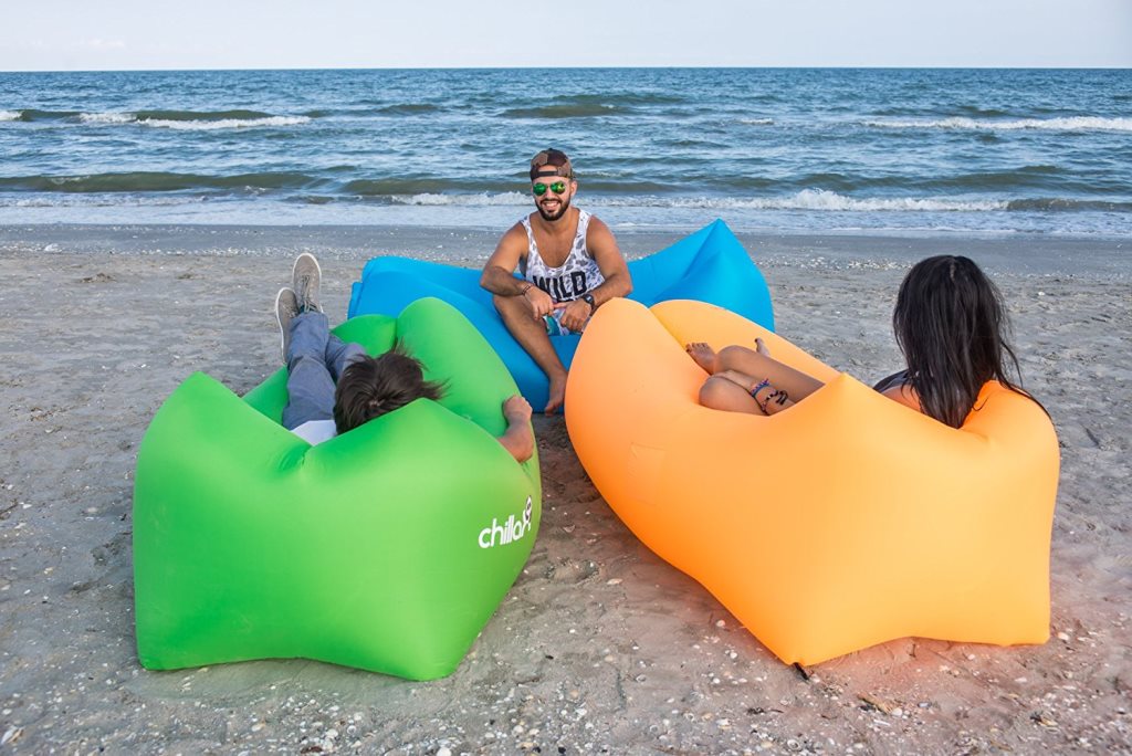 Inflatable lounge chairs in use, three young individuals lounging on the beach