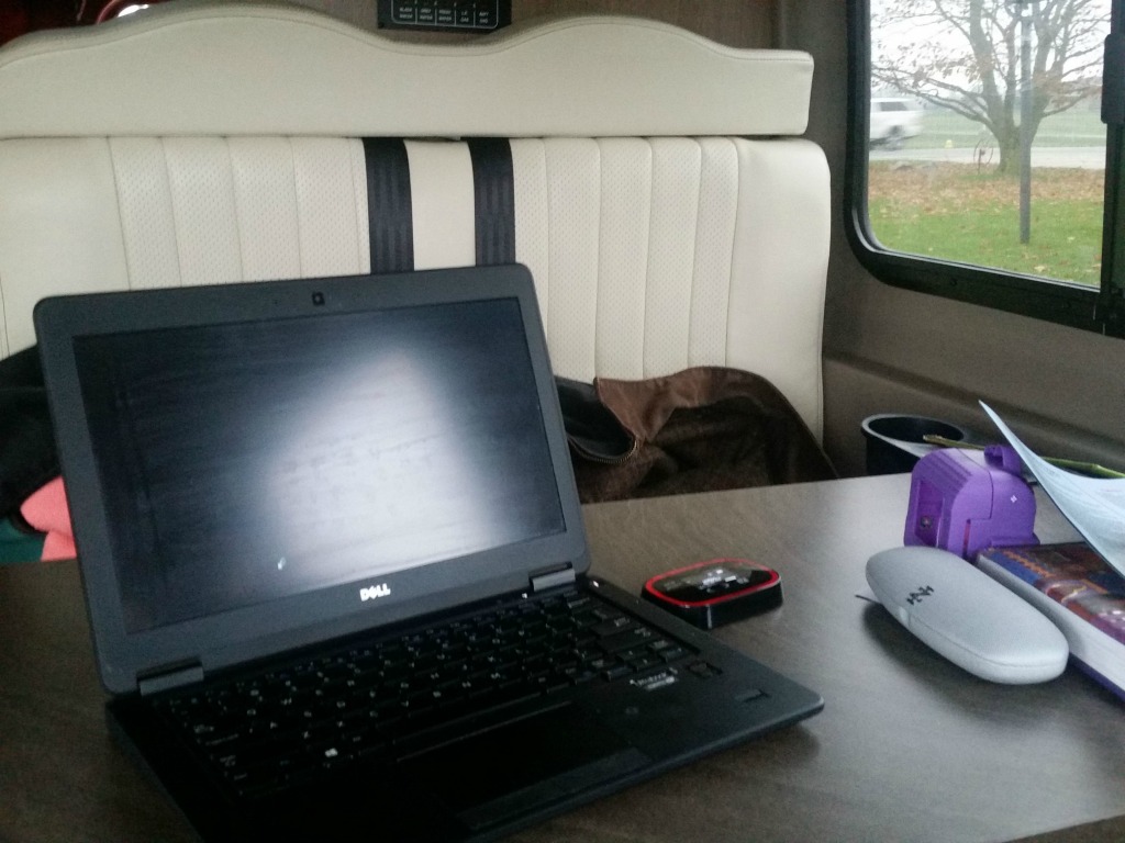Computer among other things on the dinette of the Winnebago Travato.