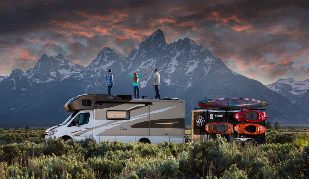 Holcombe family standing on top of their Winnebago View with the Grand Tetons in the background.