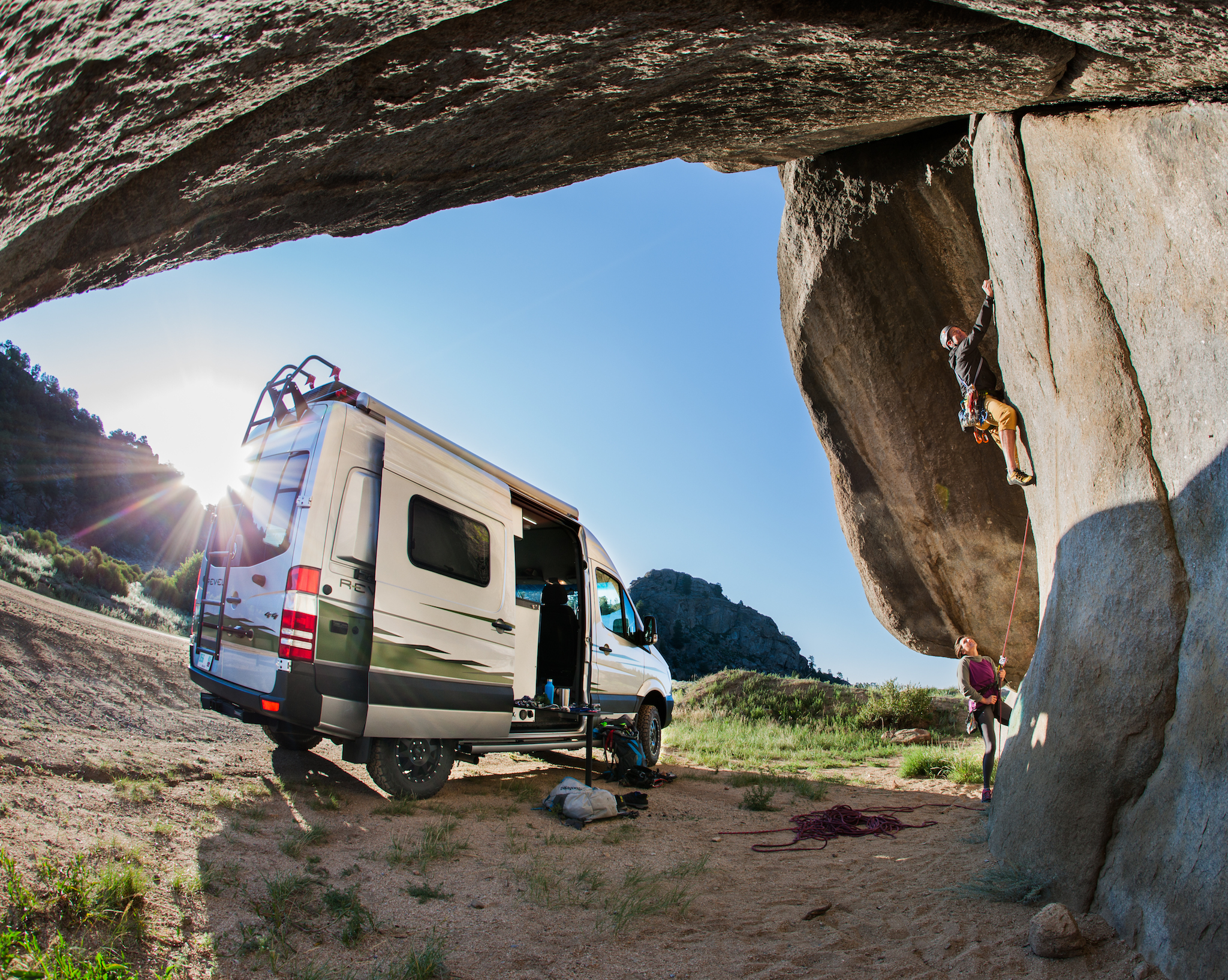 Winnebago Revel pared beneath rock formation with two people climbing the rock structures.