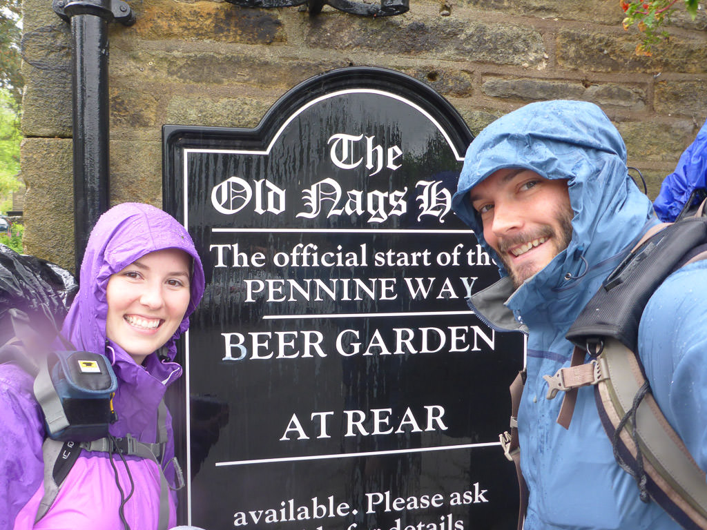 Melanie and Jeremy in rain gear by sign for the official start of the Pennine Way.