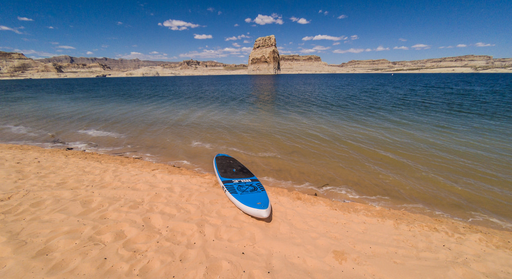 Paddleboard on beach next to water with canyons behind