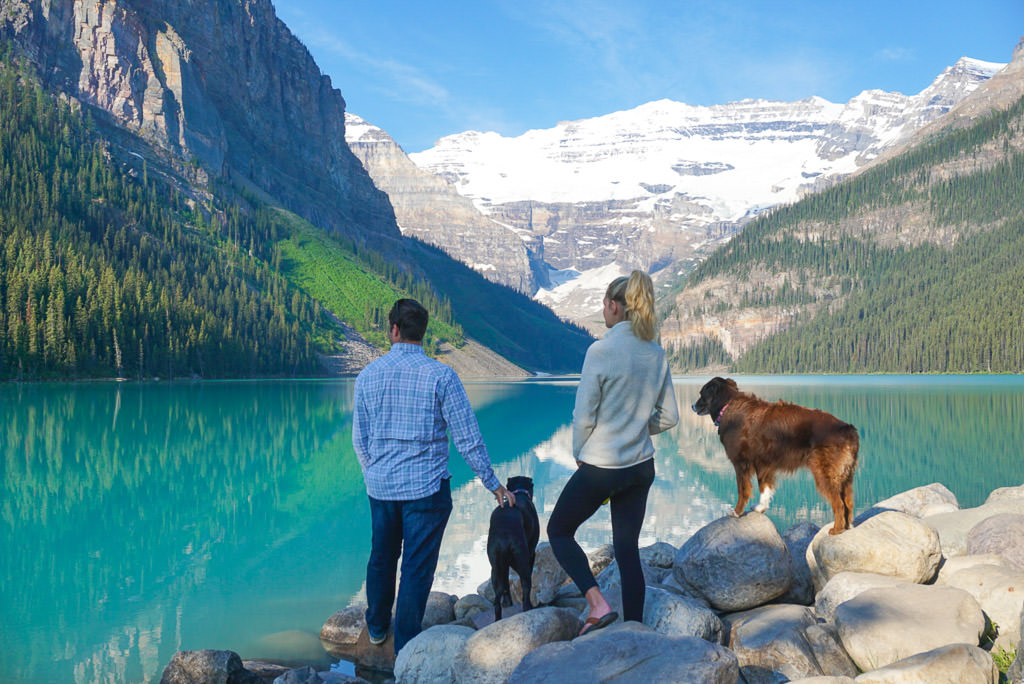 Lindsay and Dan with their two dogs looking out over the lake and mountain filled scenery