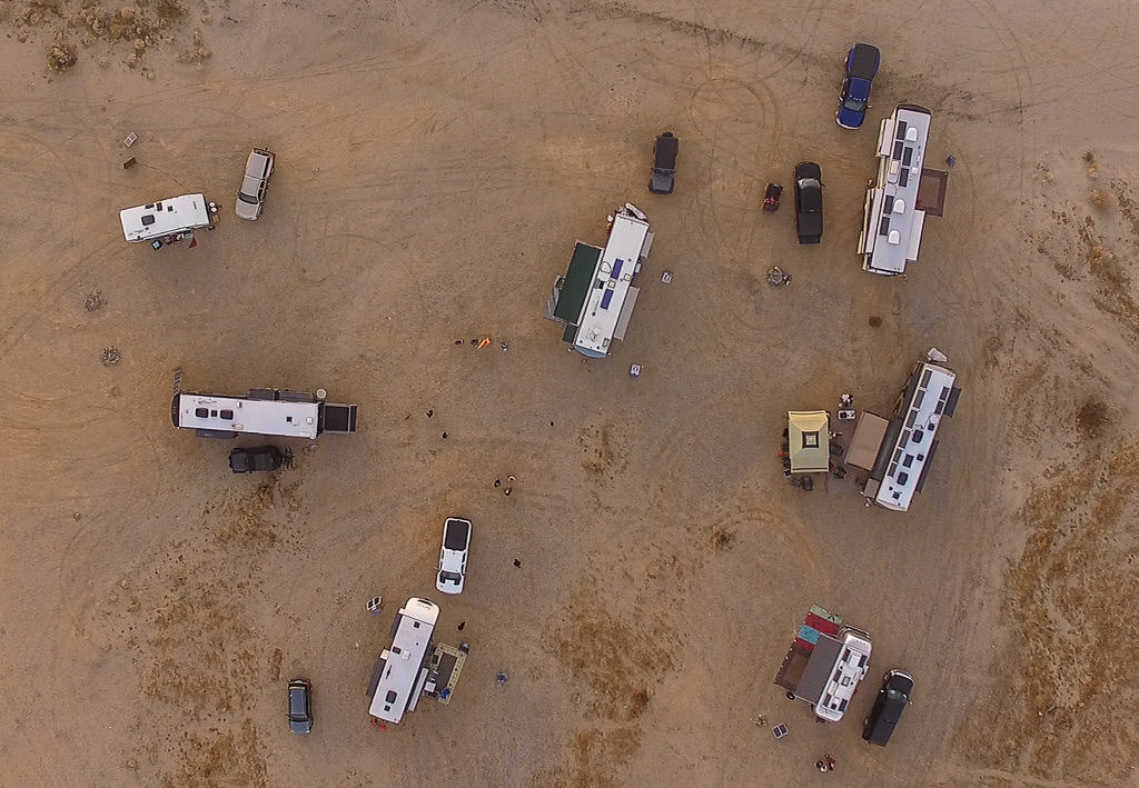 Aerial shot of seven RVs parked large gravel lot