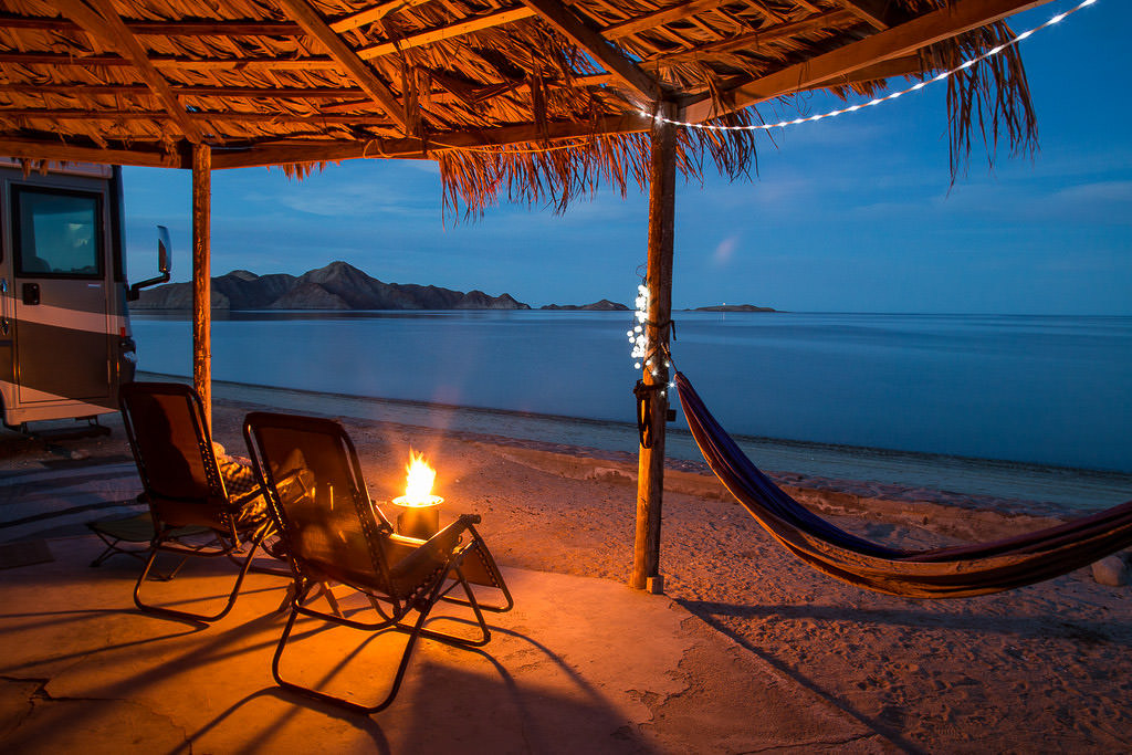 Palapa at the campsite at night with a fire going and a view of the ocean.