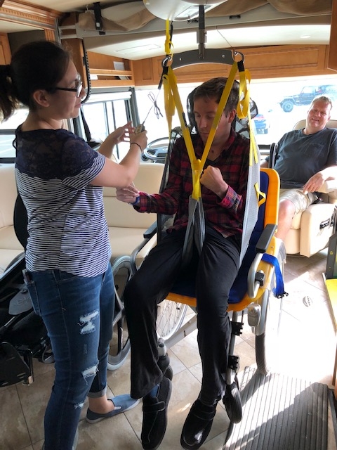 Patrick being assisted into the Winnebago Forza with a special chair lift.