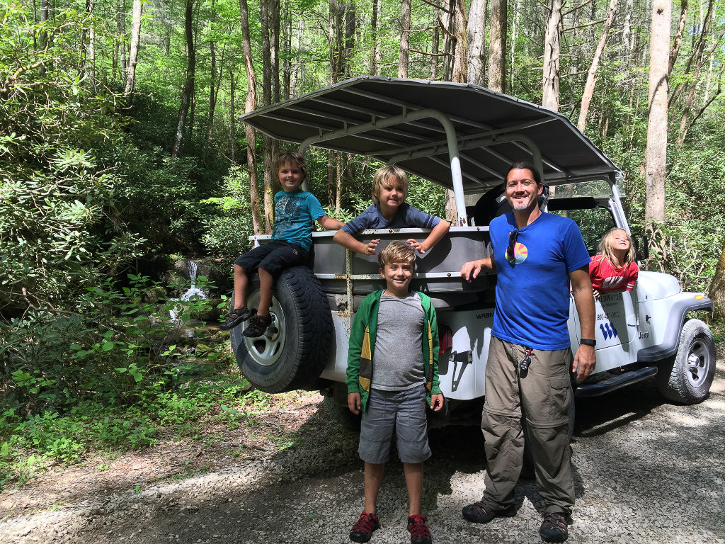 Family posing on a jeep in the middle of the woods on the Wildwater Pigeon Jeep Tour.