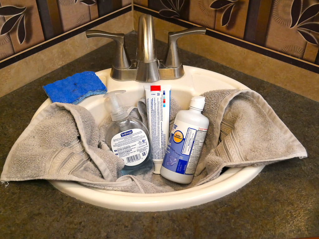 Sink with towel, hand soap, toothpaste and contact solution 