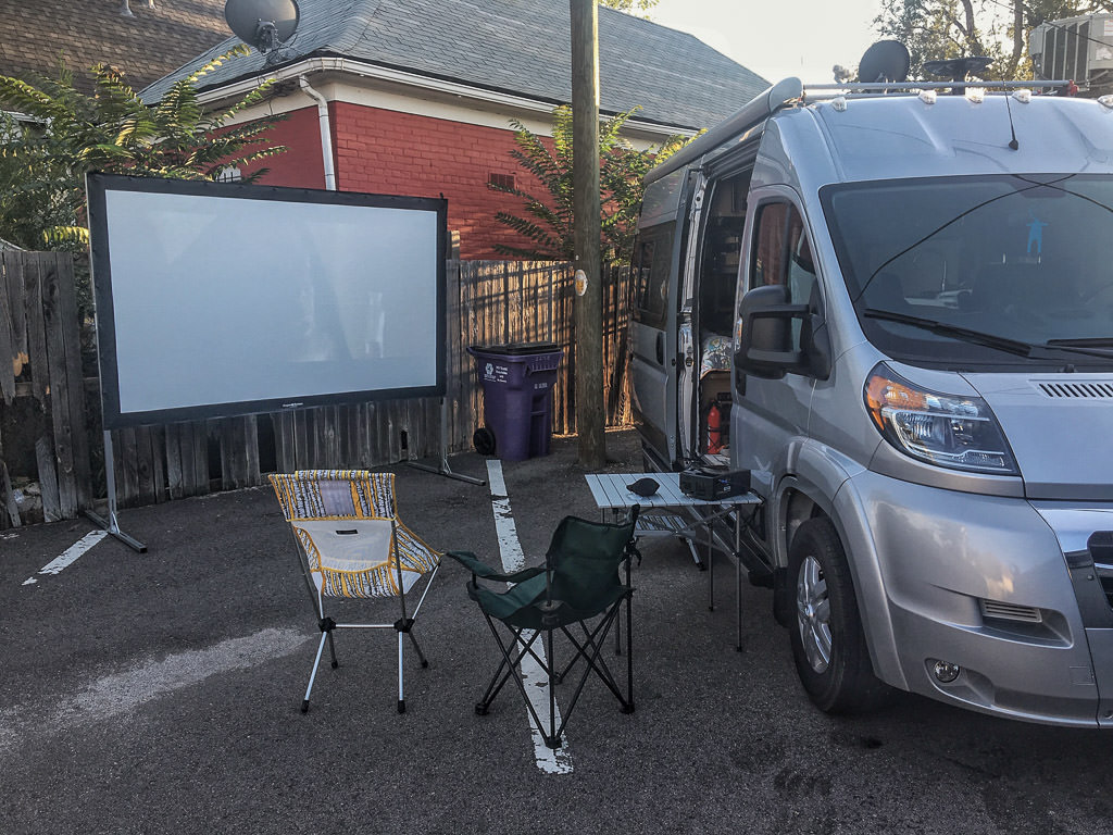 Outdoor movie setup next to a Winnebago Travato