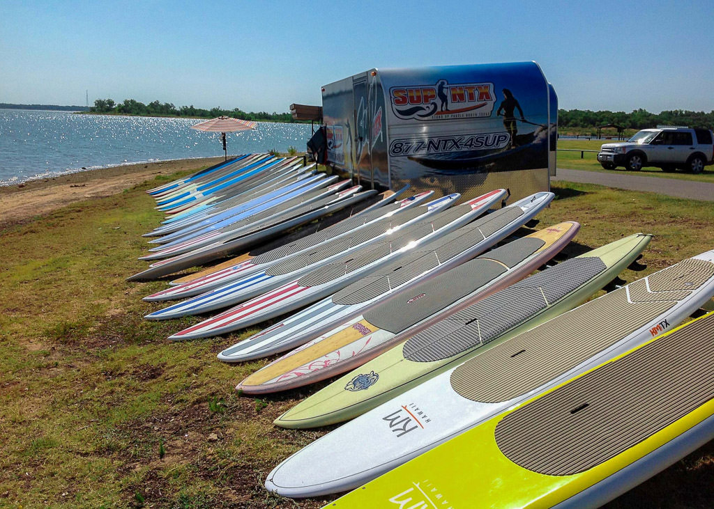 Stand up paddle boards lined up along lake