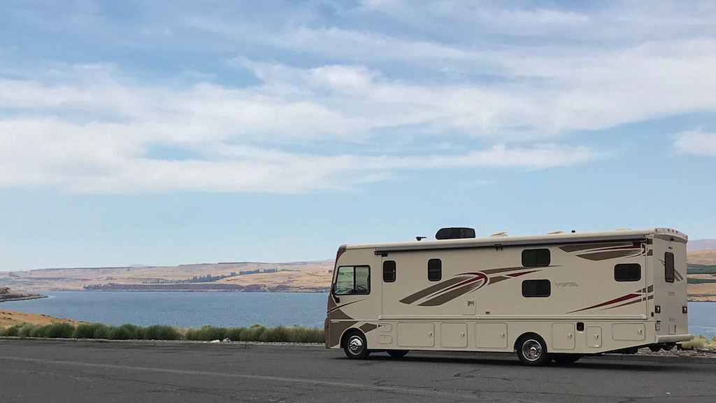 Winnebago Vista parked on the side of the road next to body of water.