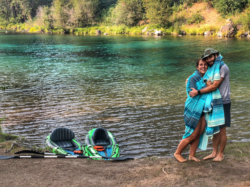 Young couple poses for picture with their inflatable kayaks on the shore of a lake 