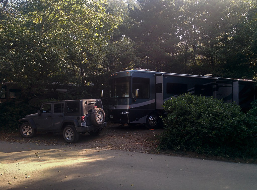 Motorhome parked in tree shaded camping spot.