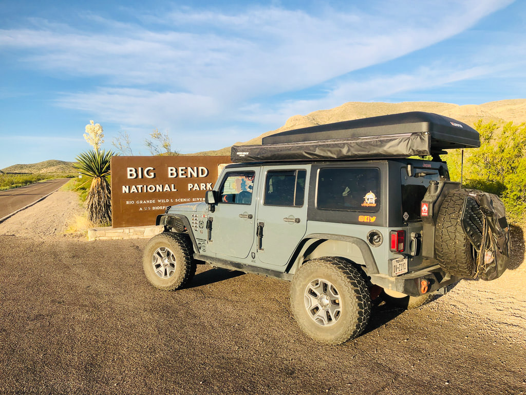 Jeep parked in front of sign for Big Bend National Park.