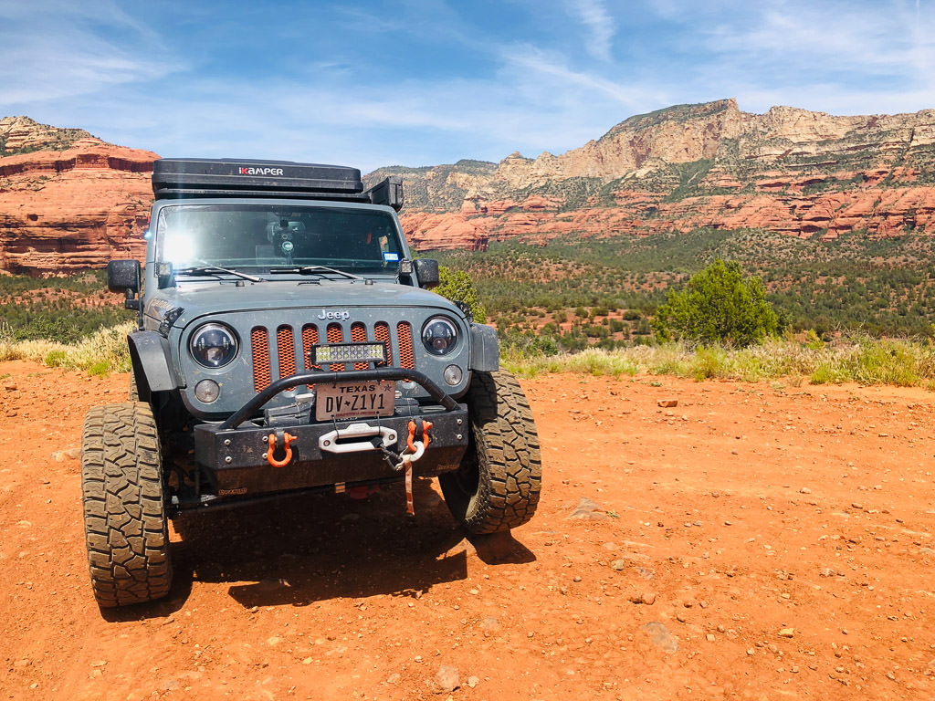 Jeep with red rock formations in the background.
