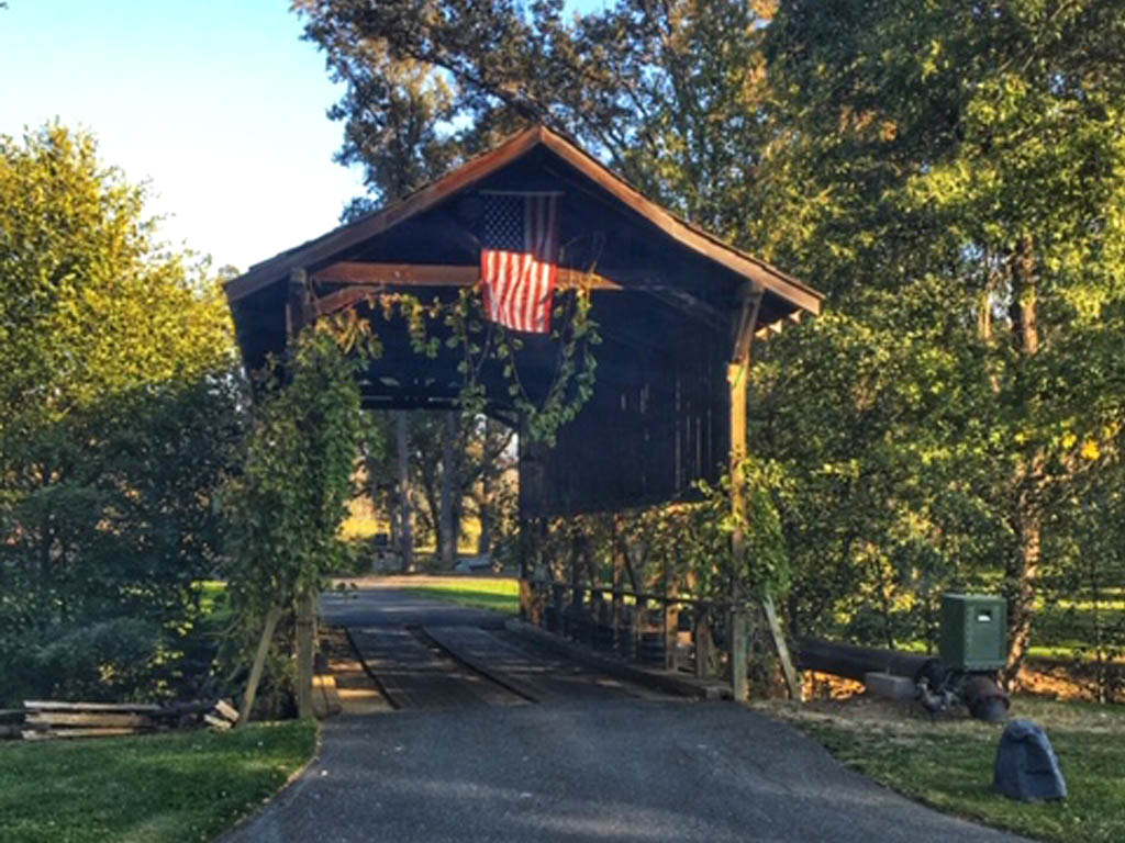 Wooden covered bridge with American flag hanging from it.